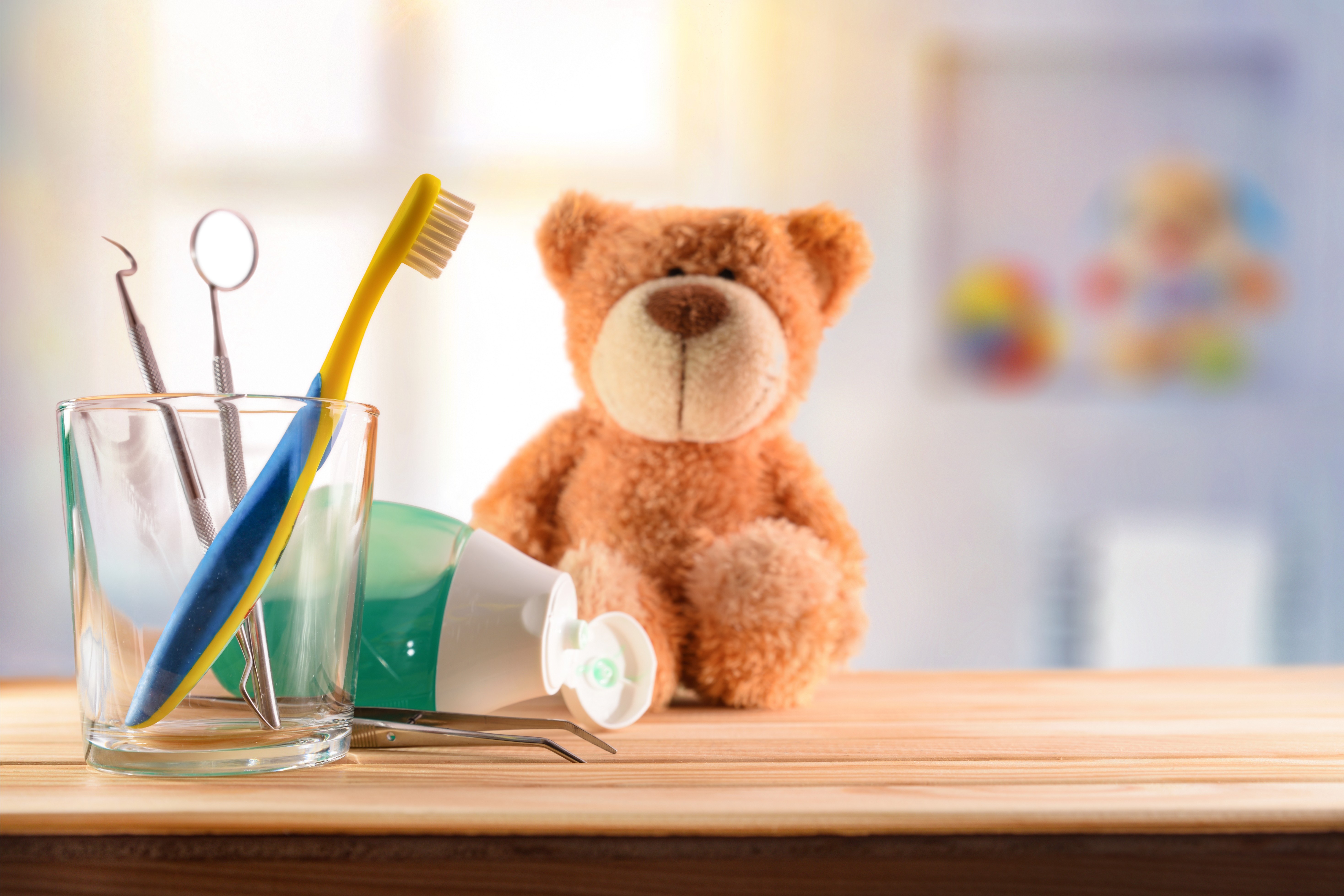 Stock photo dentist concept for children with tools in glass cup and teddy on wooden table in room with toys 1363215506